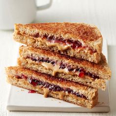 two grilled sandwiches stacked on top of each other next to a cup of coffee