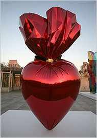 a large red heart shaped vase sitting on top of a white table