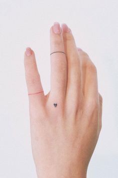 a woman's hand with a tiny black dot on the middle finger and a small ring in the middle