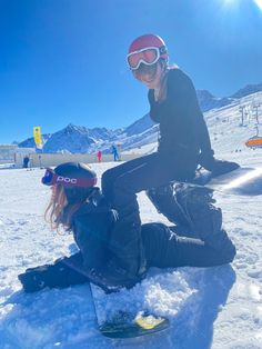 two people sitting in the snow with skis on