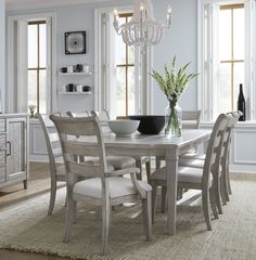 a dining room table and chairs in front of windows