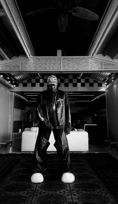 a black and white photo of a man standing in front of a ceiling fan