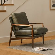 a chair sitting on top of a hard wood floor next to a stair case in a living room