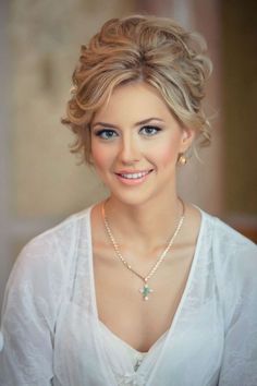 a woman with blonde hair wearing a white shirt and pearls on her necklace is smiling at the camera