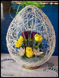 a vase filled with yellow and purple flowers on top of a table next to a body of water