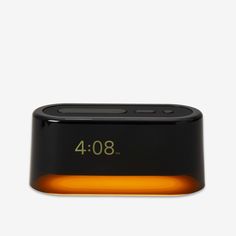 an alarm clock with the time displayed on it's display screen, and yellow light