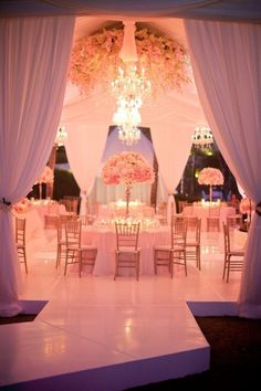 an elegant wedding setup with chandeliers and pink flowers on the ceiling is ready for guests to arrive