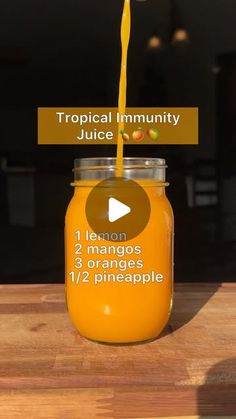 a jar filled with orange juice sitting on top of a wooden table next to a sign that says tropical community juice