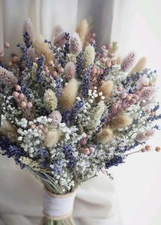 a bouquet of dried flowers sitting on top of a white cloth covered chair next to a window