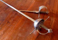 a metal object sitting on top of a wooden floor next to a knife and fork