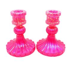 two pink glass candlesticks sitting next to each other