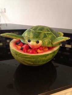 a watermelon shaped like a turtle with fruit in it's mouth