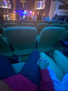 two people laying down in an auditorium with their feet up on the seats while watching tv