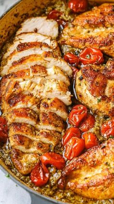 a pan filled with chicken and tomatoes on top of a table