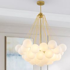 a modern chandelier with white balls hanging from it's golden metal frame