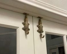 two metal gargons on the side of a white door with windows behind them