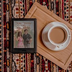 there is a cup of coffee next to a book and a tablet on the floor