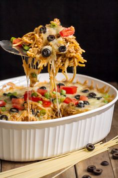 mexican spaghetti bake in a white casserole dish being lifted with a spatula