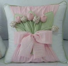 two pillows that have flowers on them and one has a pink bow around the pillow