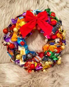 a wreath made out of candy and candies with a red bow on it sitting on a furry surface