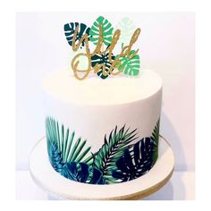 a white cake with green leaves and gold lettering