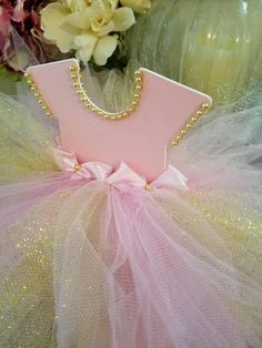 a pink and gold tutule with pearls on the bottom, sitting in front of flowers