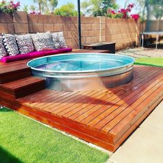 a hot tub sitting on top of a wooden deck next to a green lawn area