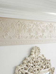 an ornate white mirror hanging on the wall