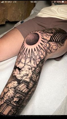 a person laying on top of a bed with a tattoo on their arm and the sun above them