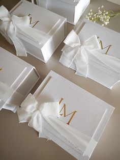 four white boxes with bows and the letter m on them are sitting on a table