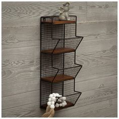 a metal wire shelf with three shelves and some balls on the floor next to it