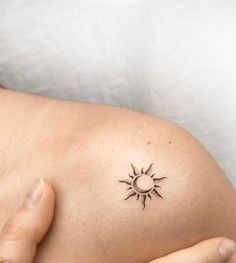 a woman's belly with a small sun tattoo on her left side ribcage