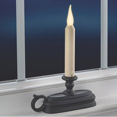 a lit candle sitting on top of a window sill