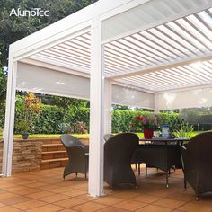 an outdoor dining area with white pergolan roof and black chairs, surrounded by greenery