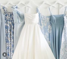 four bridesmaid dresses hanging on a wall with blue and white florals in the background