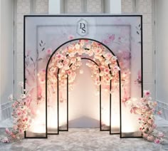 an archway decorated with pink flowers and lit up by lights in front of a white wall