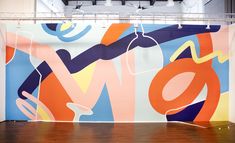 a large colorful painting on the side of a wall next to a wooden floor in an empty room