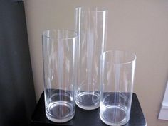 three clear glass vases sitting on top of a black table next to each other