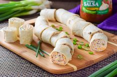 a wooden cutting board topped with rolls and veggies