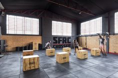 people are doing exercises in a gym with boxes on the floor and one person is running