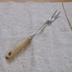 a pair of tongs sitting on top of a white towel next to a fork