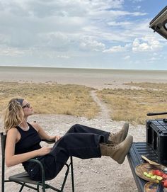 a woman sitting on a chair in front of an open camper with her feet up