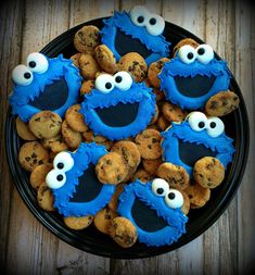 cookie cookies with blue icing and googly eyes are on a black platter