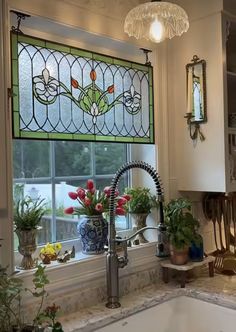 a kitchen sink under a stained glass window with flowers in the vases next to it