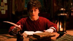 a young man sitting at a table with an open book in front of him, reading