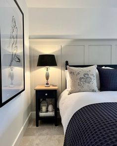 a bed room with a neatly made bed next to a night stand and a lamp