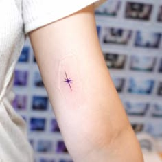 a small star tattoo on the left inner arm, with an arrow in it's center