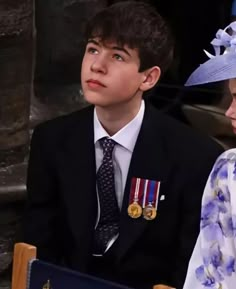 a young boy and woman sitting next to each other in front of a man wearing a blue hat