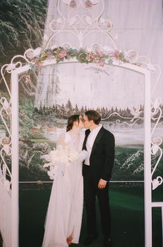 a bride and groom kissing in front of a wedding photo frame with flowers on it