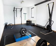 an empty gym room with black flooring and exercise equipment on the wall, including barbells